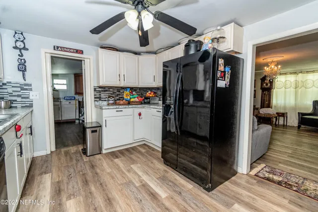 a kitchen with stainless steel appliances kitchen island granite countertop a refrigerator and a wooden floor