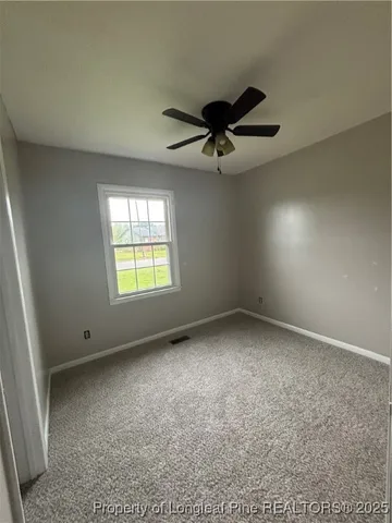 an empty room with windows and ceiling fan