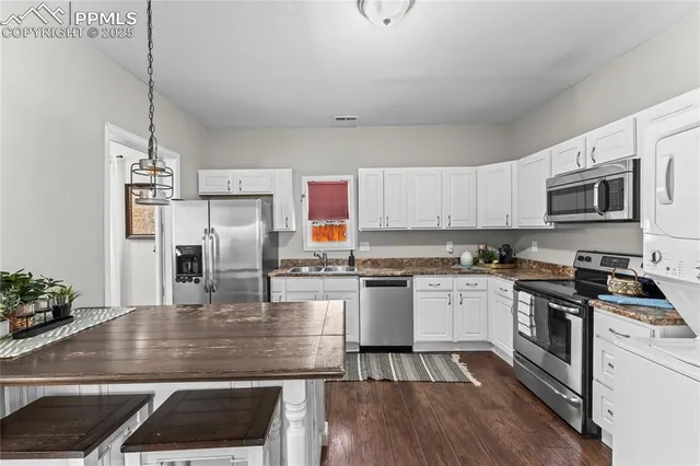 a kitchen with granite countertop a stove a sink dishwasher a refrigerator and a dining table with wooden floor