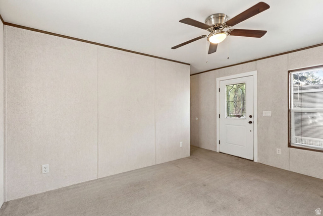 2875 North Hill Field Road, Unit 62 Layton, UT 84041 - Photo 9 of 34 Neutral-toned panel walls with wood trim, featuring a ceiling fan with light fixture, a white door with decorative glass insert, and a window with blinds