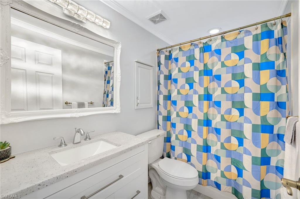 613 Windsor Square, Unit 101 Naples, FL 34104 - Photo 12 of 22 a bathroom with a granite countertop sink a toilet and a mirror