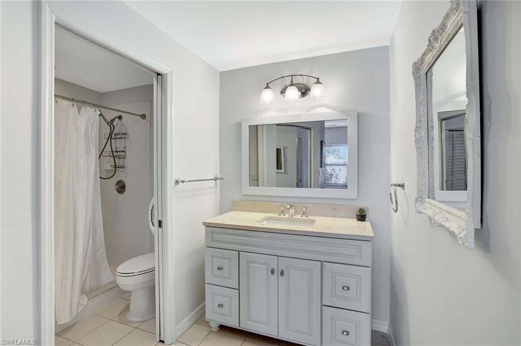 613 Windsor Square, Unit 101 Naples, FL 34104 - Photo 14 of 22 a bathroom with a toilet sink double vanity and mirror