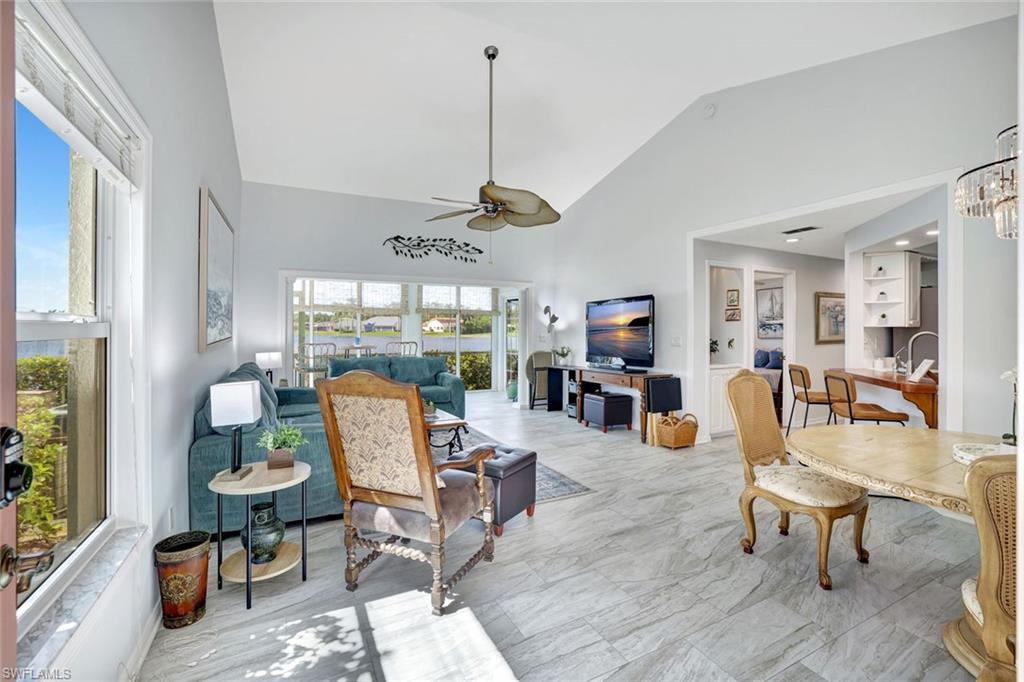 613 Windsor Square, Unit 101 Naples, FL 34104 - Photo 8 of 22 a dining room with wooden floor a chandelier a glass table and chairs