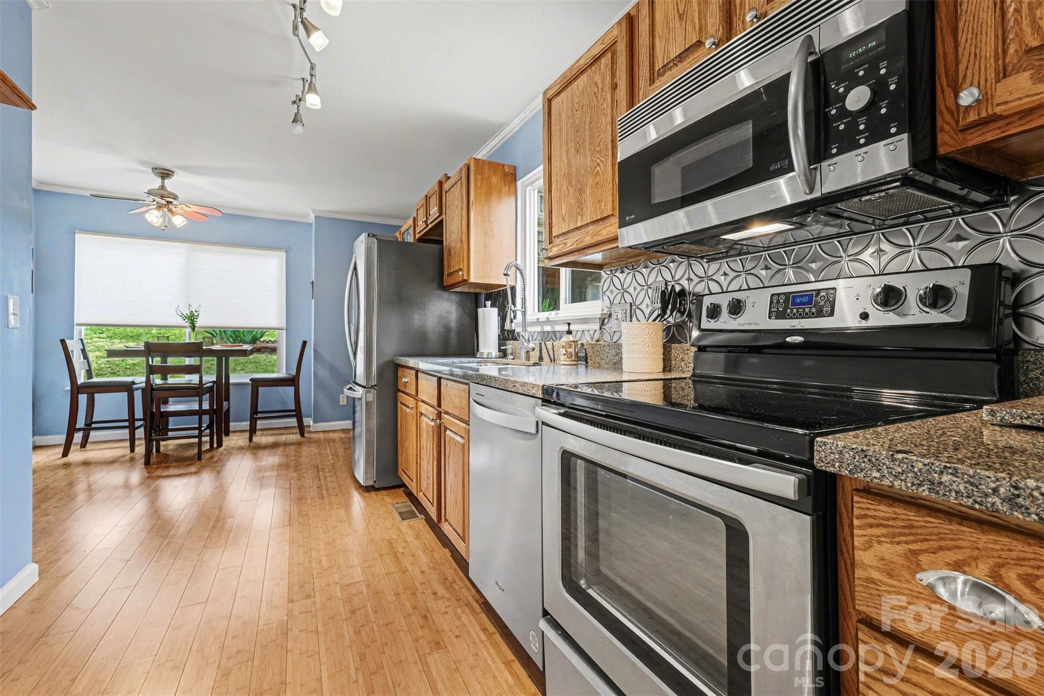 26030 Misty Way Drive Tega Cay, SC 29708 - Photo 9 of 43 a kitchen with stainless steel appliances granite countertop a stove top oven a sink dishwasher a dining table and chairs with wooden floor