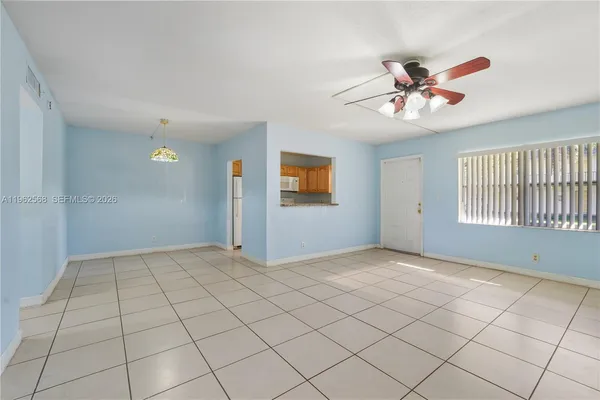 an empty room with a chandelier fan and glass door