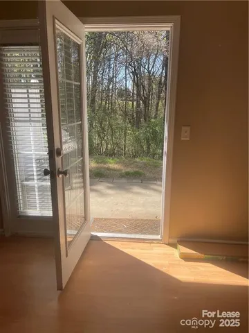 a view of empty room with wooden floor and a window