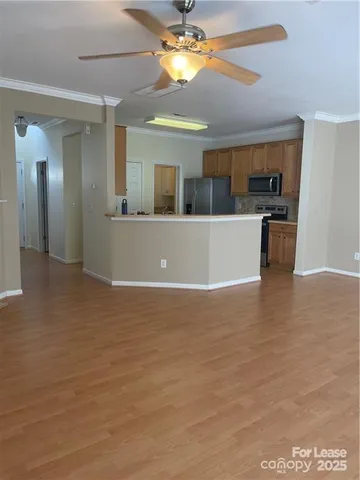 a view of kitchen and empty room with wooden floor