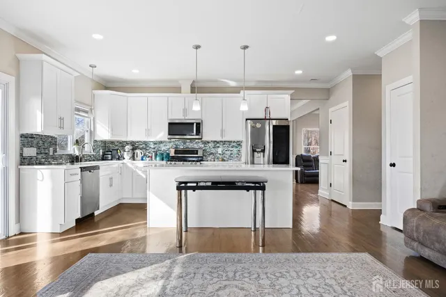 a kitchen with stainless steel appliances granite countertop a refrigerator a stove and white cabinets with wooden floor