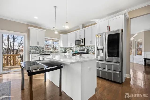 a kitchen with stainless steel appliances granite countertop a refrigerator a stove a sink a dining table and chairs with wooden floor