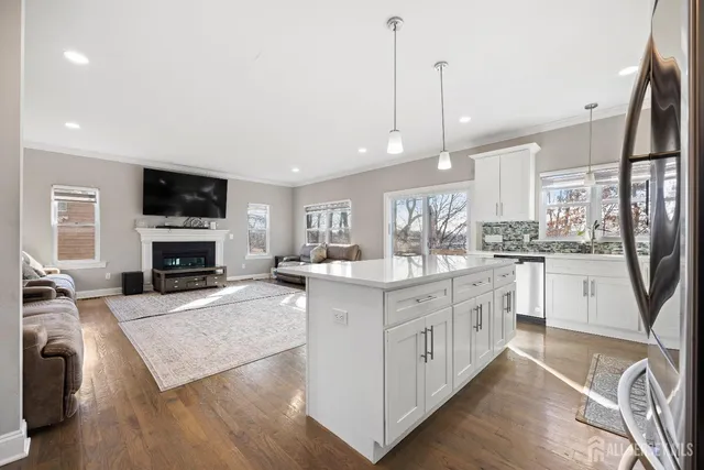 a large kitchen with stainless steel appliances granite countertop a stove top oven a sink dishwasher and a refrigerator with wooden floor