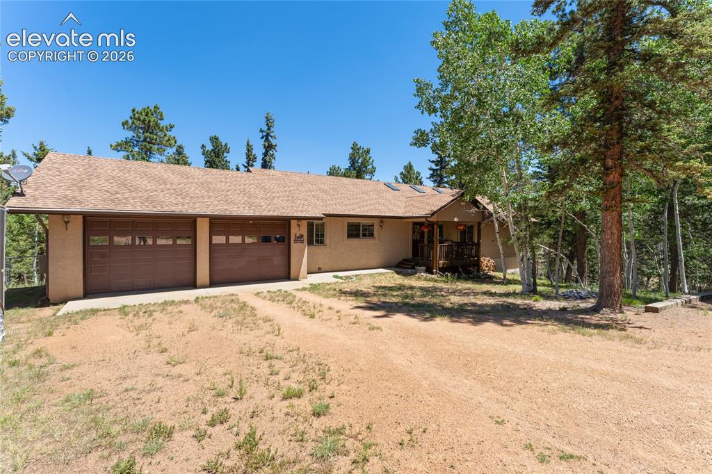 657 Spring Valley Drive Divide, CO 80814 - Photo 1 of 43 Ranch-style exterior with a two-car garage, covered porch, and mature trees