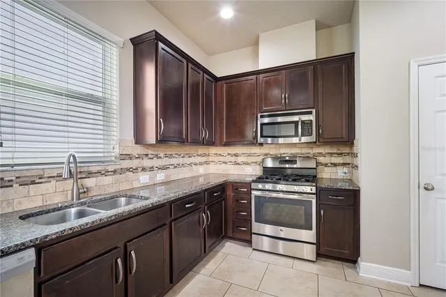 a kitchen with stainless steel appliances granite countertop a stove microwave and sink