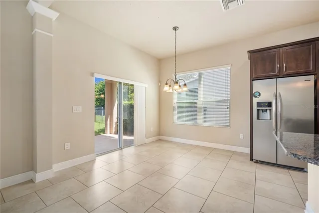 a view of an empty room with window and chandelier