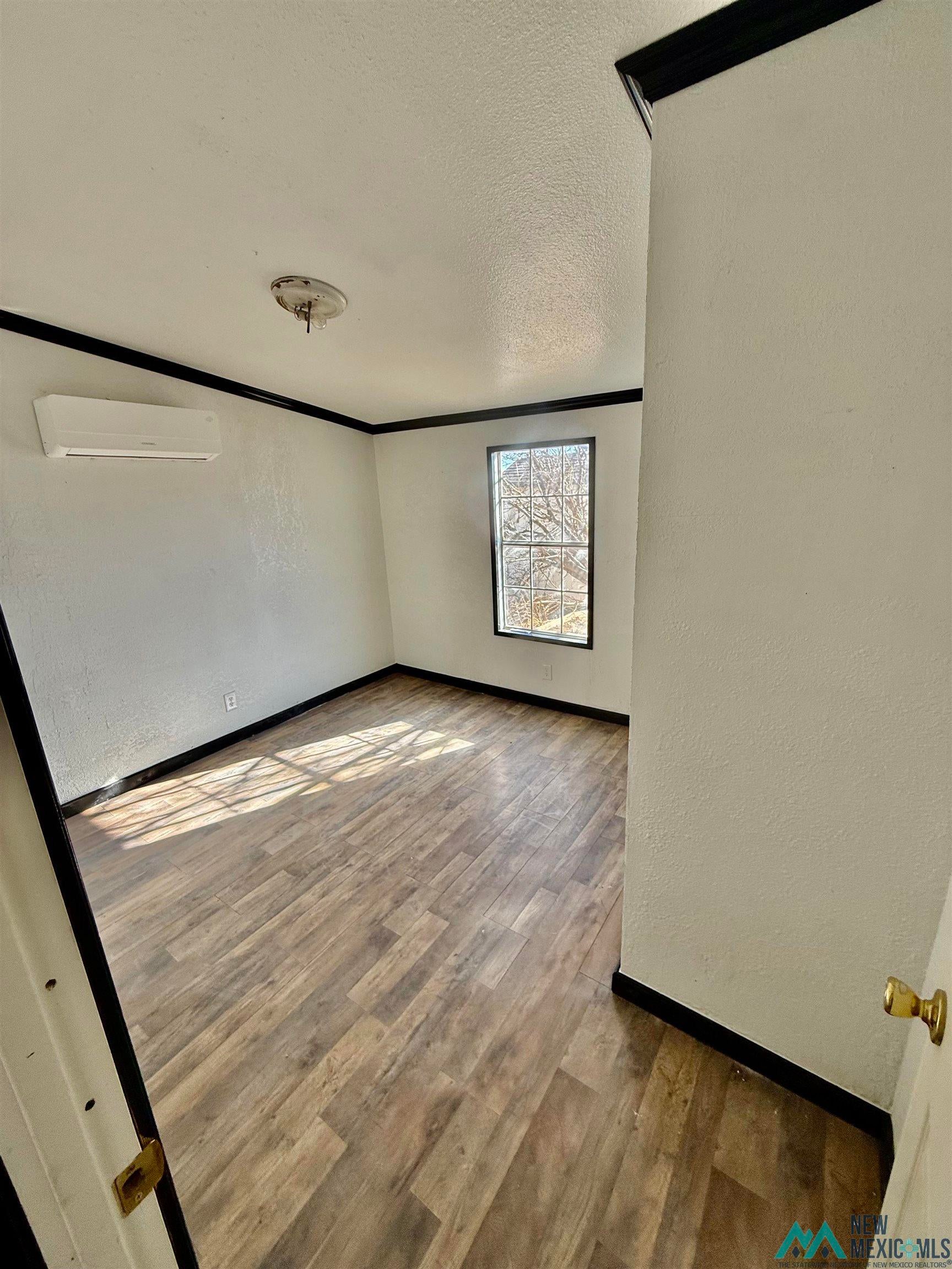 207 Chuckwagon Road Carlsbad, NM 88220 - Photo 7 of 19 Unfurnished room with a textured wall, a textured ceiling, and wood finished floors