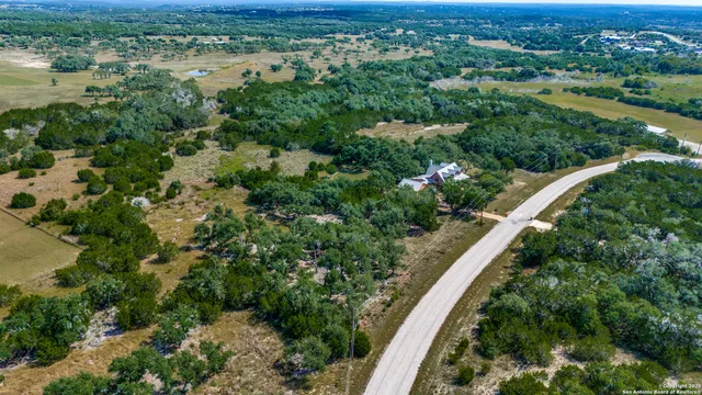 an aerial view of residential houses with outdoor space and trees