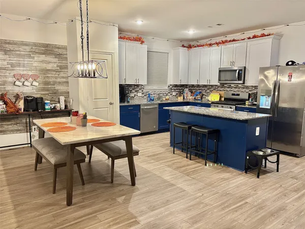 a kitchen with stainless steel appliances kitchen island granite countertop a table chairs sink refrigerator and microwave