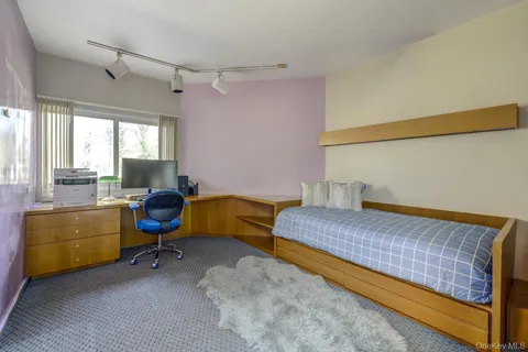 a bedroom with a bed chair and a dresser next to a window