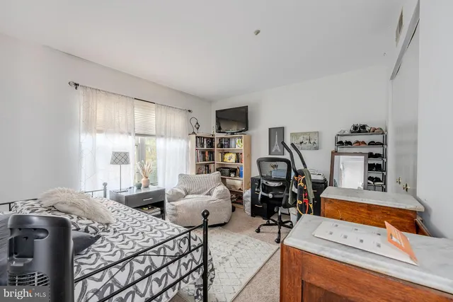 a bedroom with a bed and dresser with chair