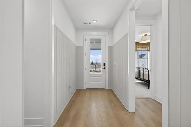 a view of a hallway with wooden floor kitchen and windows