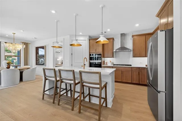 a kitchen with stainless steel appliances kitchen island granite countertop a table chairs and a refrigerator