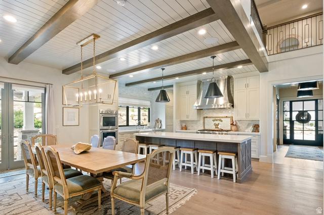 3 Carriagewood Cove, Unit 1088 Sandy, UT 84092 - Photo 21 of 79 Open-concept interior featuring wood-finish flooring, a shiplap ceiling with exposed beams, a kitchen island with seating, a built-in oven, and a balcony with an iron railing