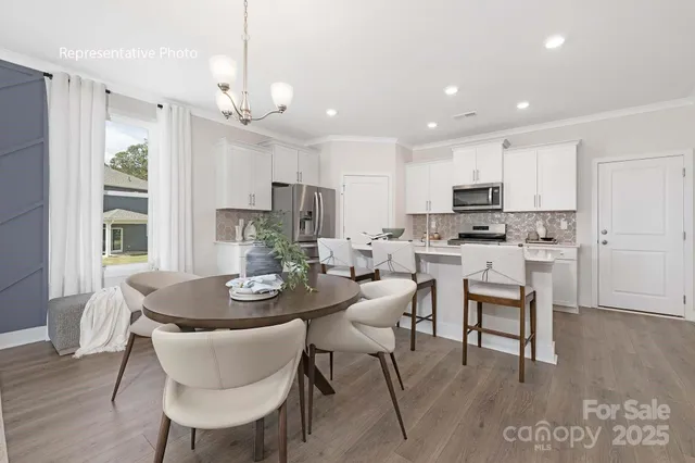 a dining room with kitchen island a dining table wooden floor and a refrigerator