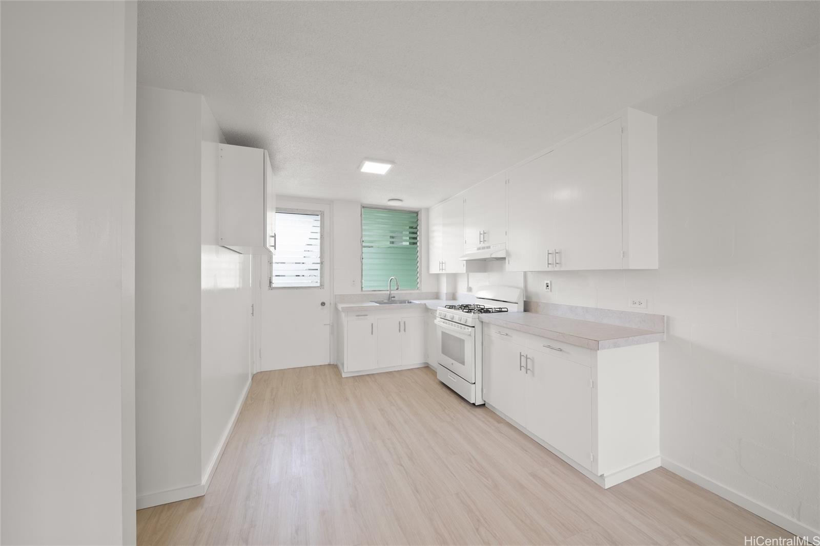 a kitchen with white cabinets and wooden floor