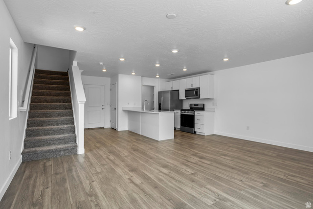 2194 Wolverine Way, Unit 2531 Washington, UT 84780 - Photo 6 of 52 Open-concept living space featuring wood-finish flooring, recessed lighting, a functional kitchen island, white cabinetry, and stainless steel appliances