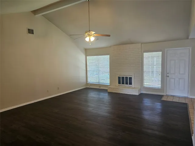 an empty room with wooden floor chandelier fan and windows