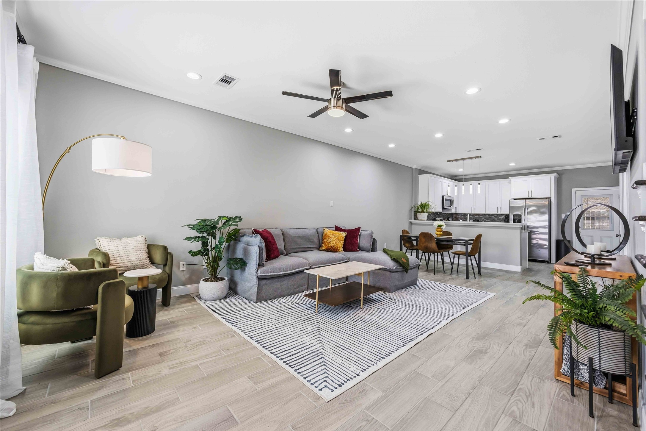 4903 Mallow Street, Unit A Houston, TX 77033 - Photo 3 of 10 This open-concept living room features a bright, modern design that seamlessly transitions into the dining and kitchen areas. The living area is part of a large, fluid space that includes a dining set and a kitchen with white cabinetry and stainless steel appliances.