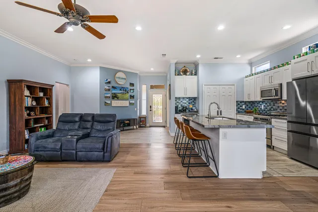 a living room with stainless steel appliances furniture and a kitchen view