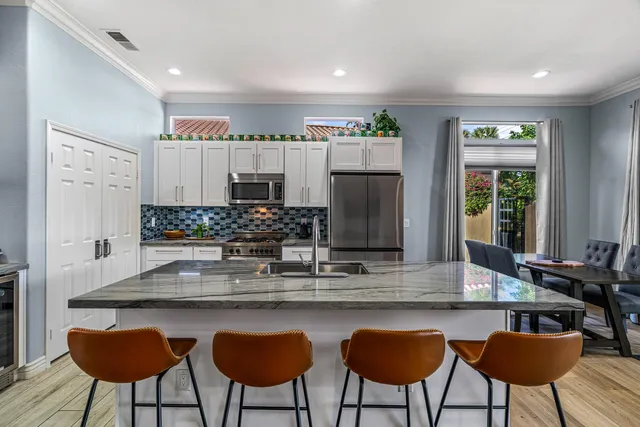 a kitchen with stainless steel appliances granite countertop a table chairs sink and cabinets