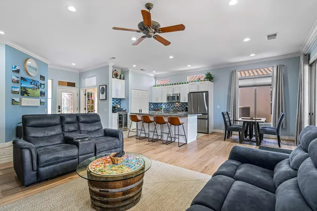 a living room with furniture kitchen view and a wooden floor