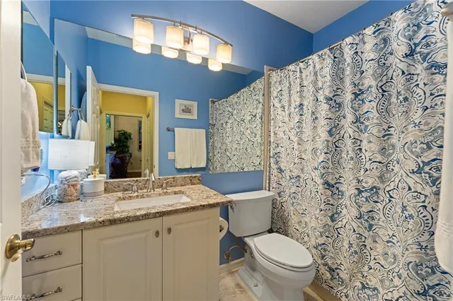 a bathroom with a granite countertop toilet a sink and a mirror