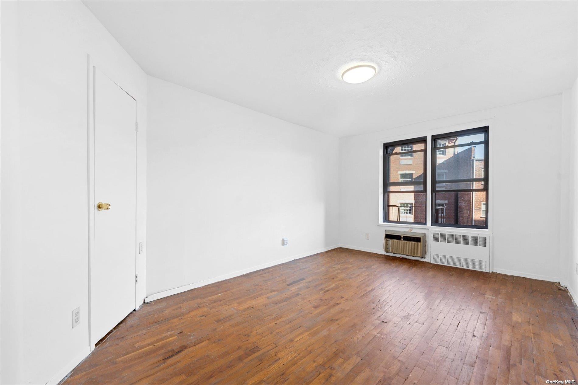 58-03 Calloway Street, Unit B3 Queens, NY 11368 - Photo 5 of 8 an empty room with wooden floor and windows
