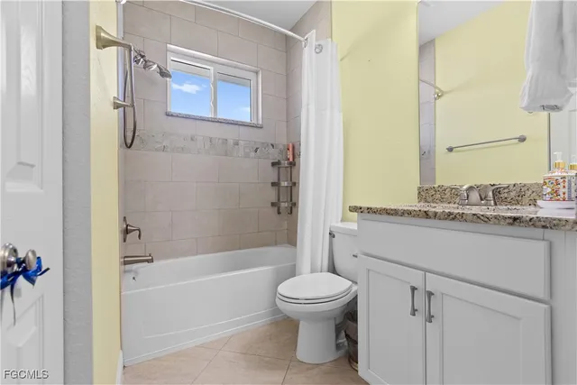 a bathroom with a granite countertop bathtub shower sink vanity and toilet