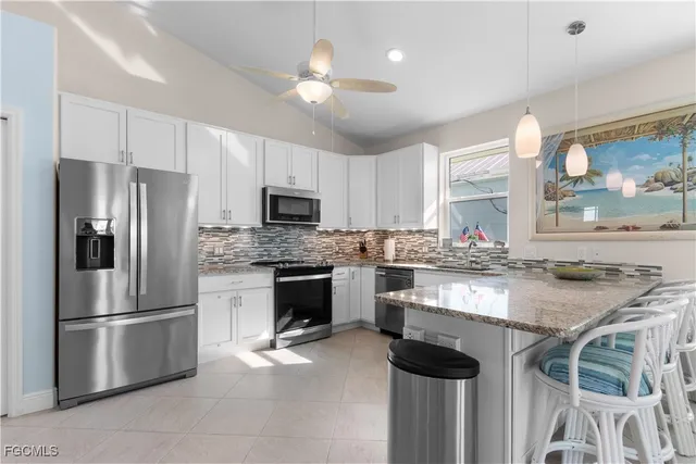 a kitchen with stainless steel appliances granite countertop a stove refrigerator sink and microwave