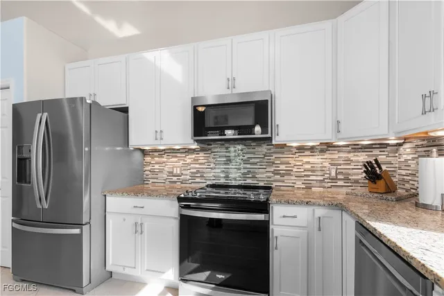a kitchen with granite countertop a refrigerator stove and microwave