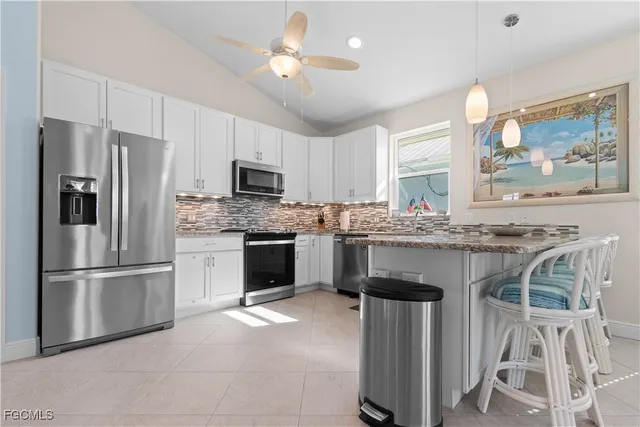 a kitchen with kitchen island granite countertop a stove a sink a refrigerator and a refrigerator