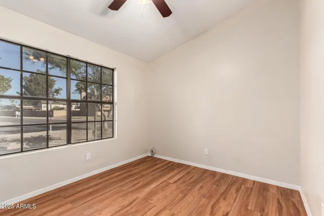 a view of an empty room with a window and wooden floor