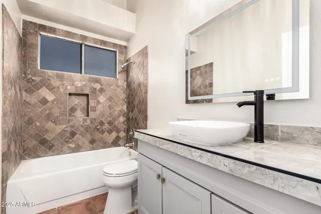 a bathroom with a granite countertop sink a toilet and bathtub