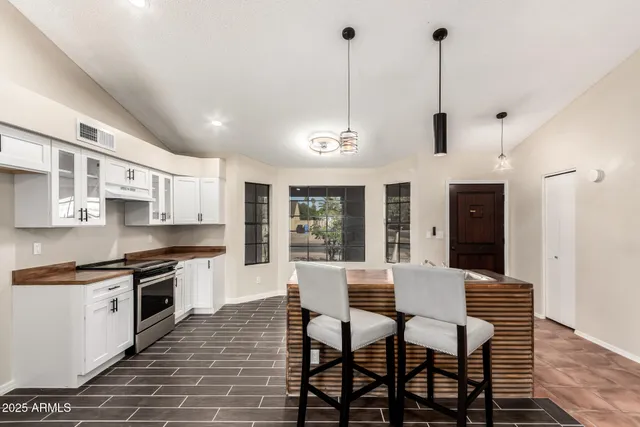 a kitchen with stainless steel appliances granite countertop a stove top oven a sink a dining table and chairs