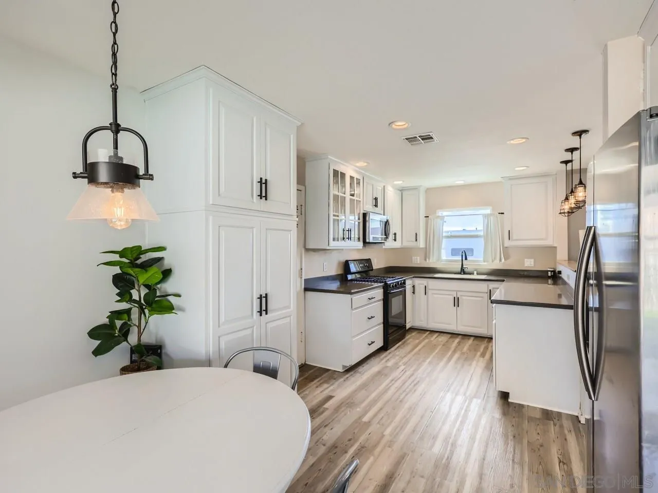 9456 Domer Road Santee, CA 92071 - Photo 7 of 30 a kitchen with a refrigerator and a wooden floor