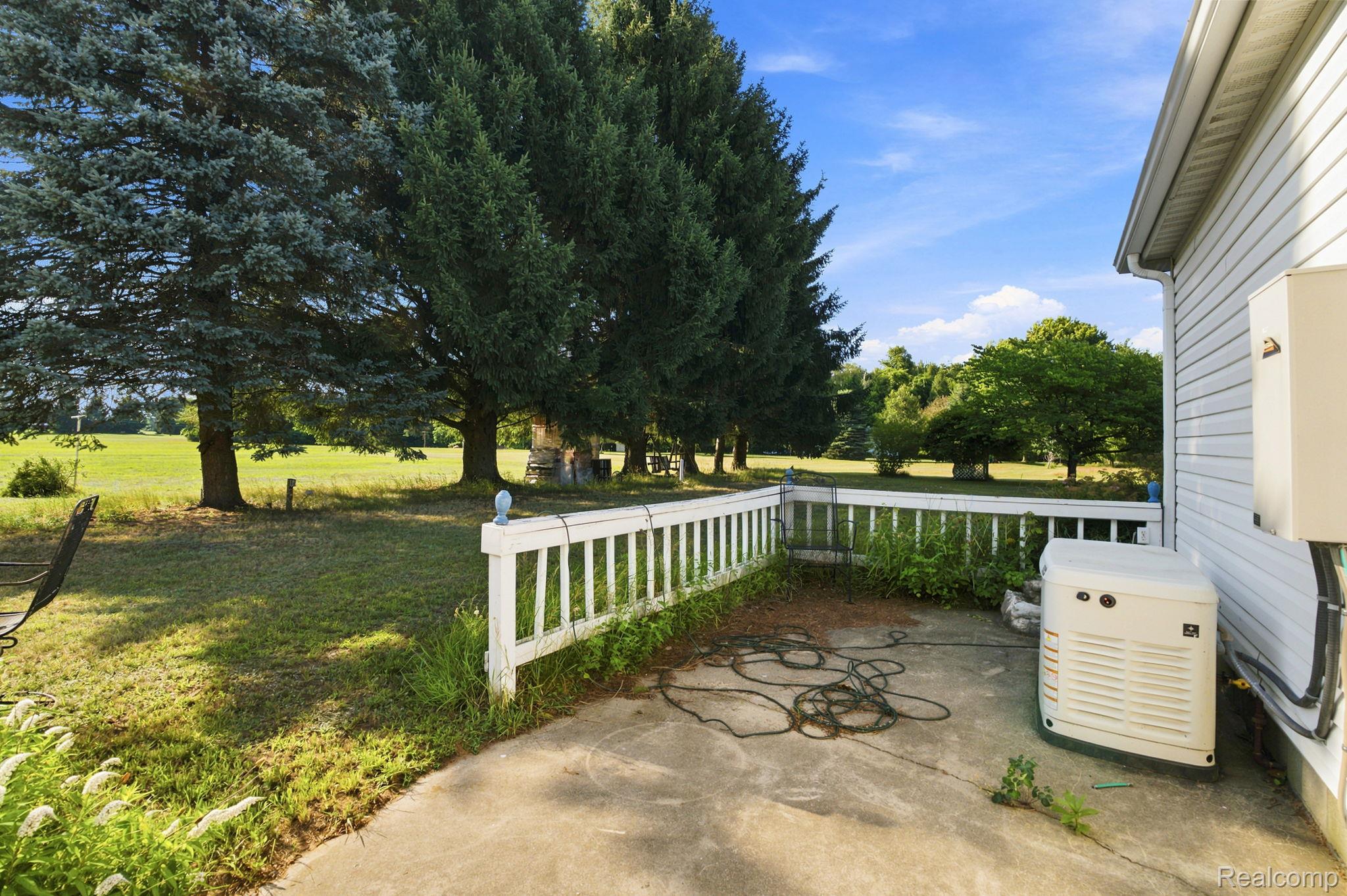 2390 Lakeshore Road Applegate, MI 48401 - Photo 81 of 97 Spacious outdoor living area featuring a white vinyl railing system, concrete patio, and mature tree-lined landscape