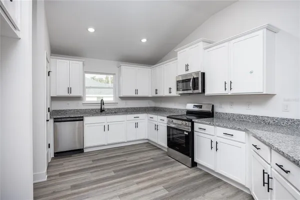 a kitchen with granite countertop white cabinets and stainless steel appliances