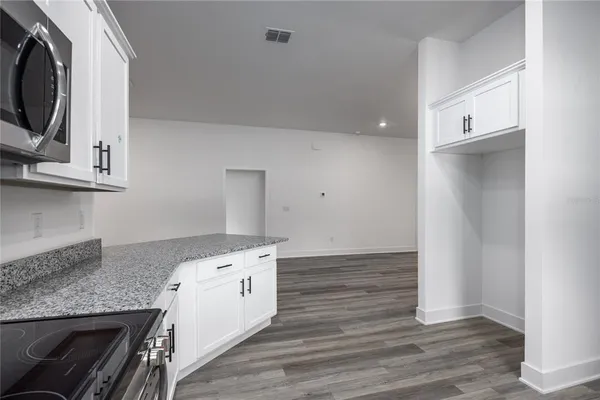 a kitchen with granite countertop a white stove top oven and wooden floor