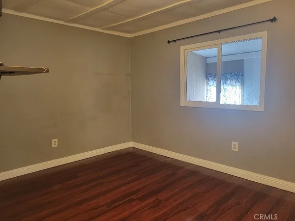 an empty room with wooden floor and a bathroom