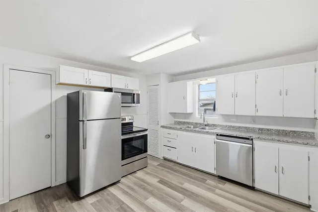 a kitchen with granite countertop white cabinets and stainless steel appliances