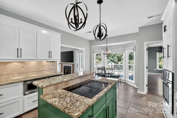 a kitchen with stainless steel appliances granite countertop a stove oven and a view of living room