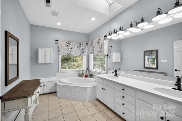 a bathroom with a double vanity sink mirror bathtub and next to a window